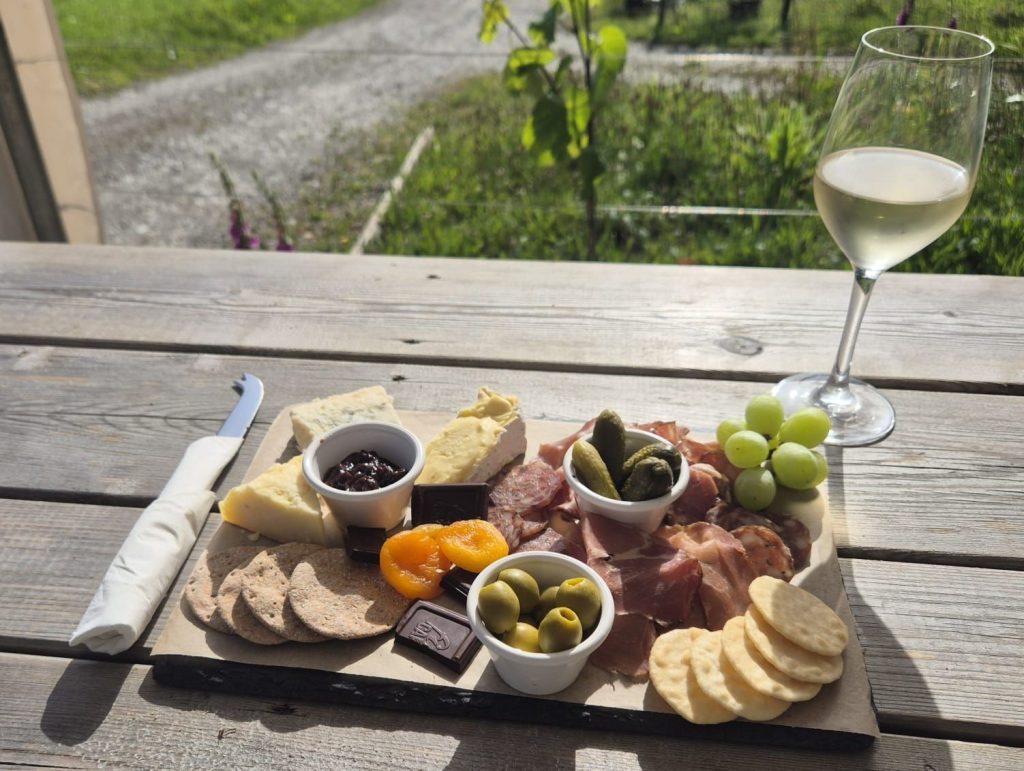 Cheese and Charcuterie board with a glass of white wine in the sun